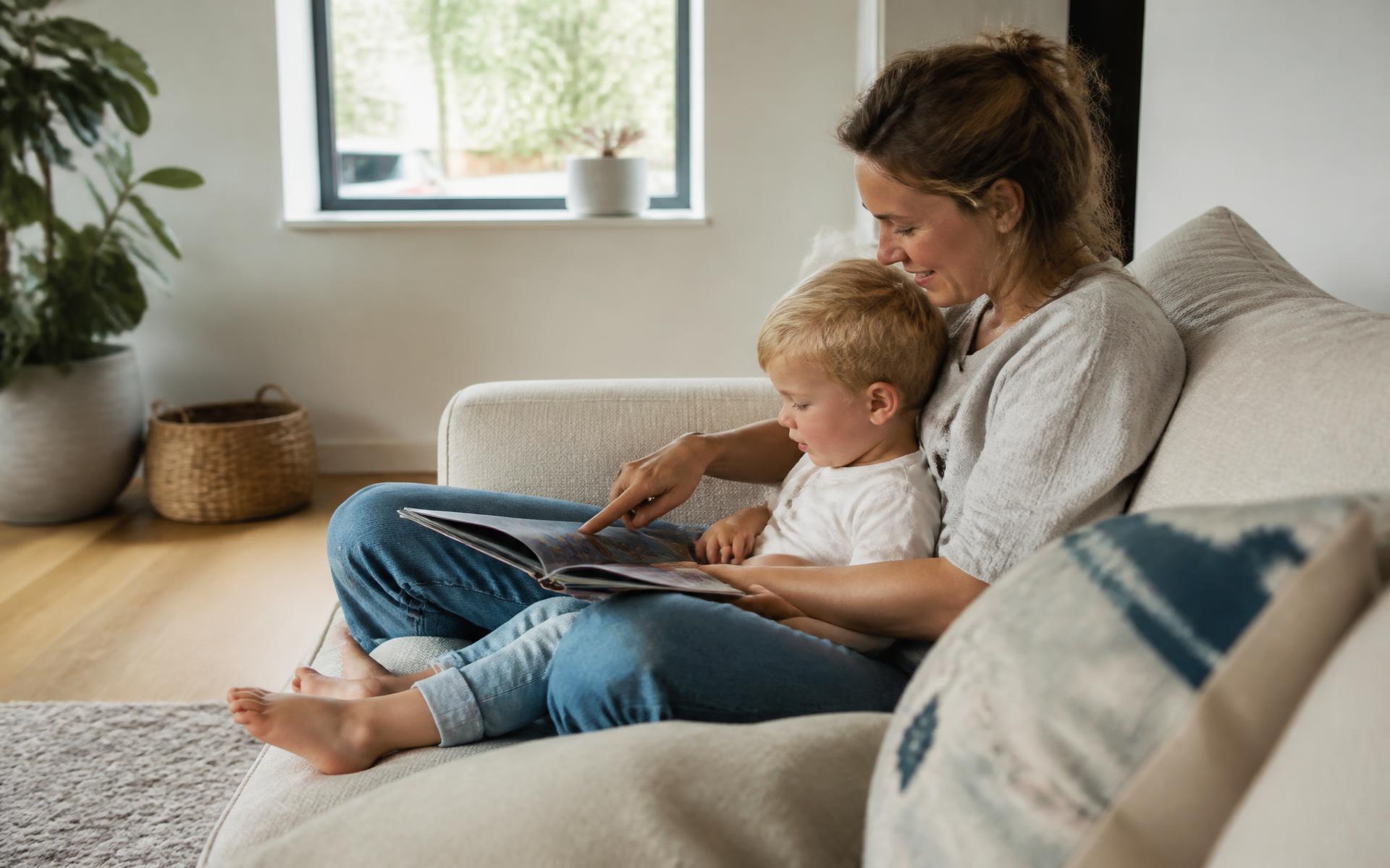Ouder en kind kijken samen rustig een boek in een lichte, moderne woonkamer